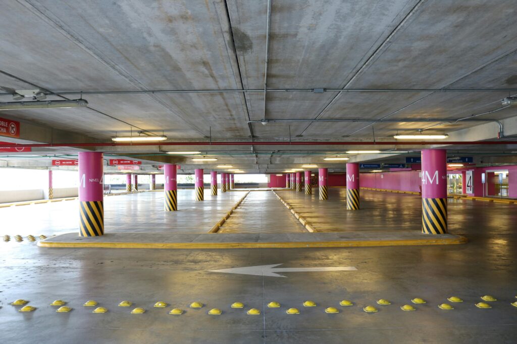 Empty indoor parking deck with pink pillars and clear directional signs in Santo Domingo.