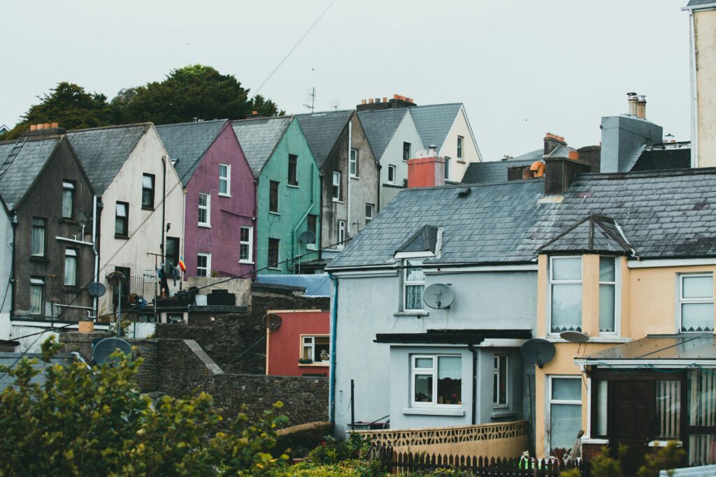 A row of vibrantly colored houses with satellite dishes and weathered facades in a peaceful residential area.