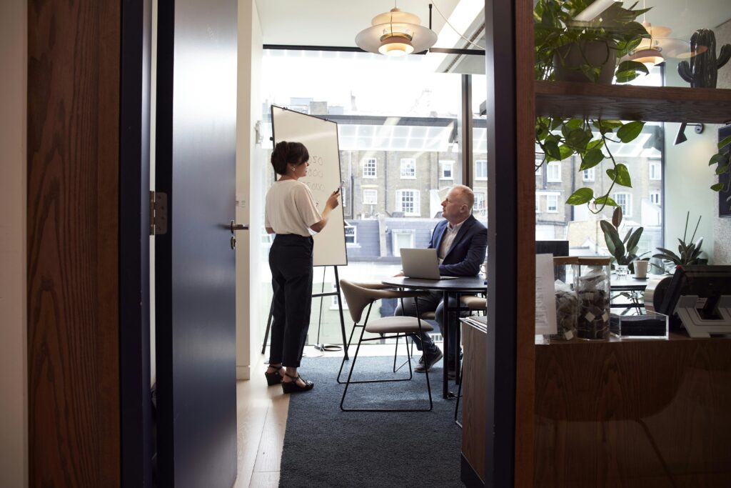 Colleagues engage in a strategic business meeting in a contemporary London office with city views.