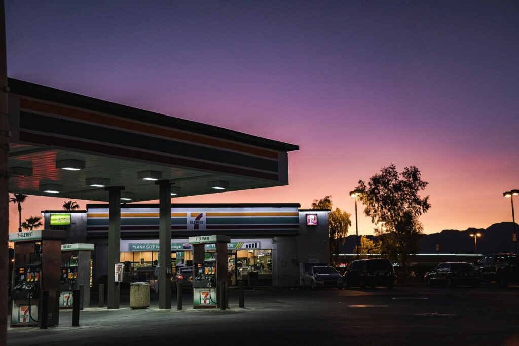 A gas station at dusk with a vibrant sunset background in an urban area.