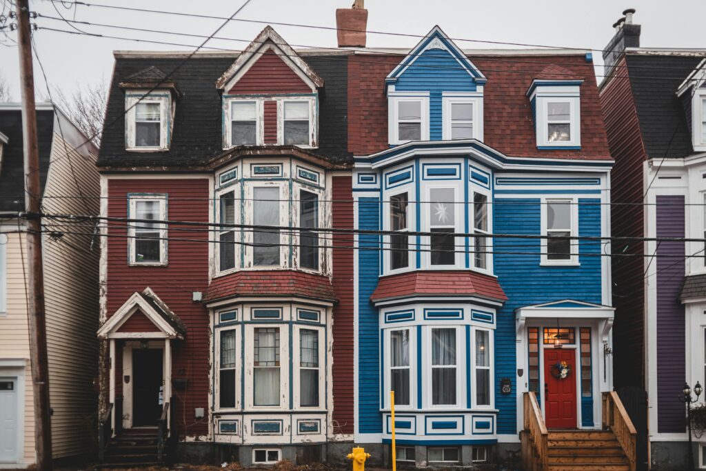 Facade of colorful old fashioned residential house with windows and doors located on street with power lines in town against cloudless sky